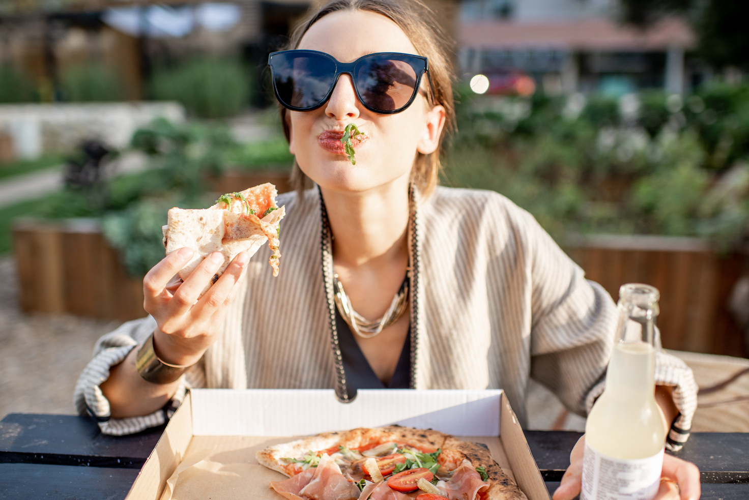 Woman eating pizza outdoors